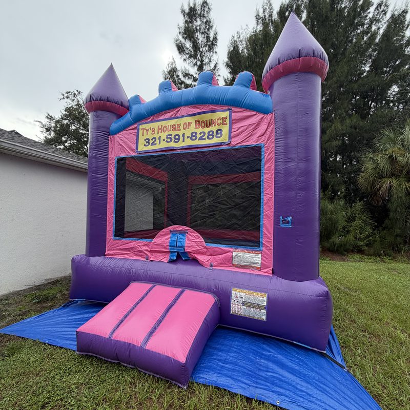 Purple and pink bounce house castle with a Ty&rsquo;s House of Bounce banner
